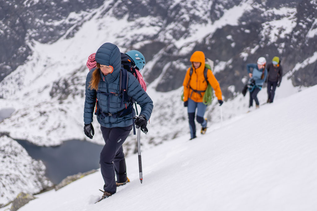 Modrá dámská bunda péřová bunda Rab Mythic Alpine při horském přechodu